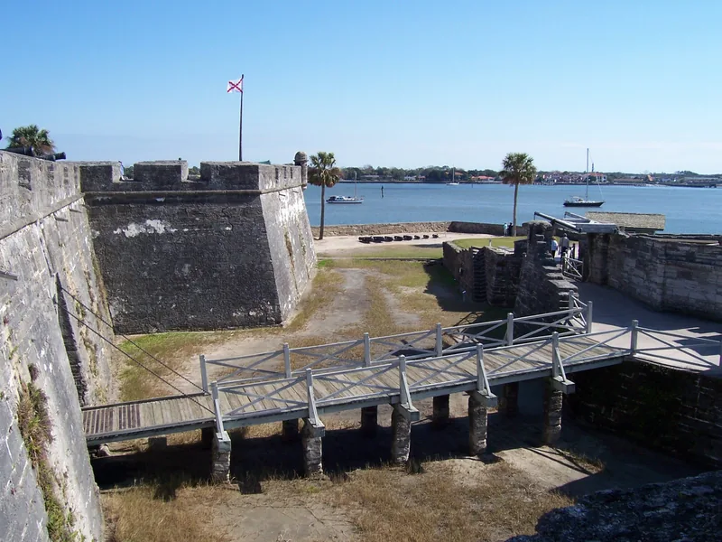 A wooden drawbridge crosses the moat beside the Castillo masonry walls.